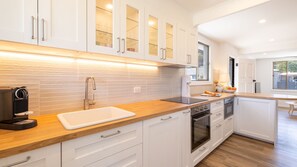 Eine moderne Küche mit weißen Schränken, einer Holz Arbeitsplatte und einem eingebauten Ofen.