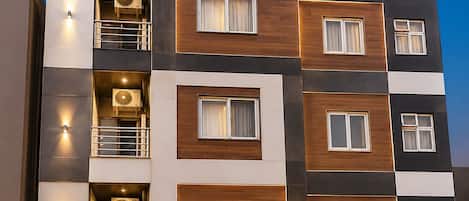 A multi-story hotel with balconies, air conditioning units, and a sign reading 'HOTEL LA RIO DELHI'.