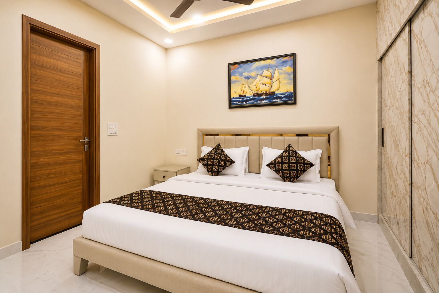 A bedroom with a bed, a nightstand, a wooden door, a painting, and marble walls.