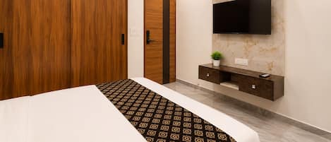 A bedroom with a bed, wardrobe, TV, and a small plant.