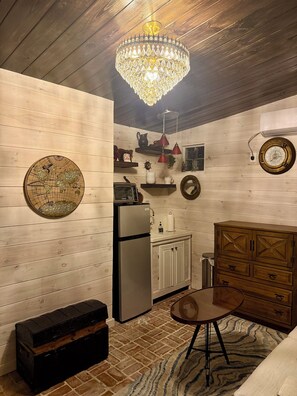 A compact kitchen with a refrigerator, a wooden cabinet, a globe wall decoration, a clock, and a chandelier. - Cozy 1-bedroom studio in fantastic Bay St. Louis with AC (Bay St. Louis)
