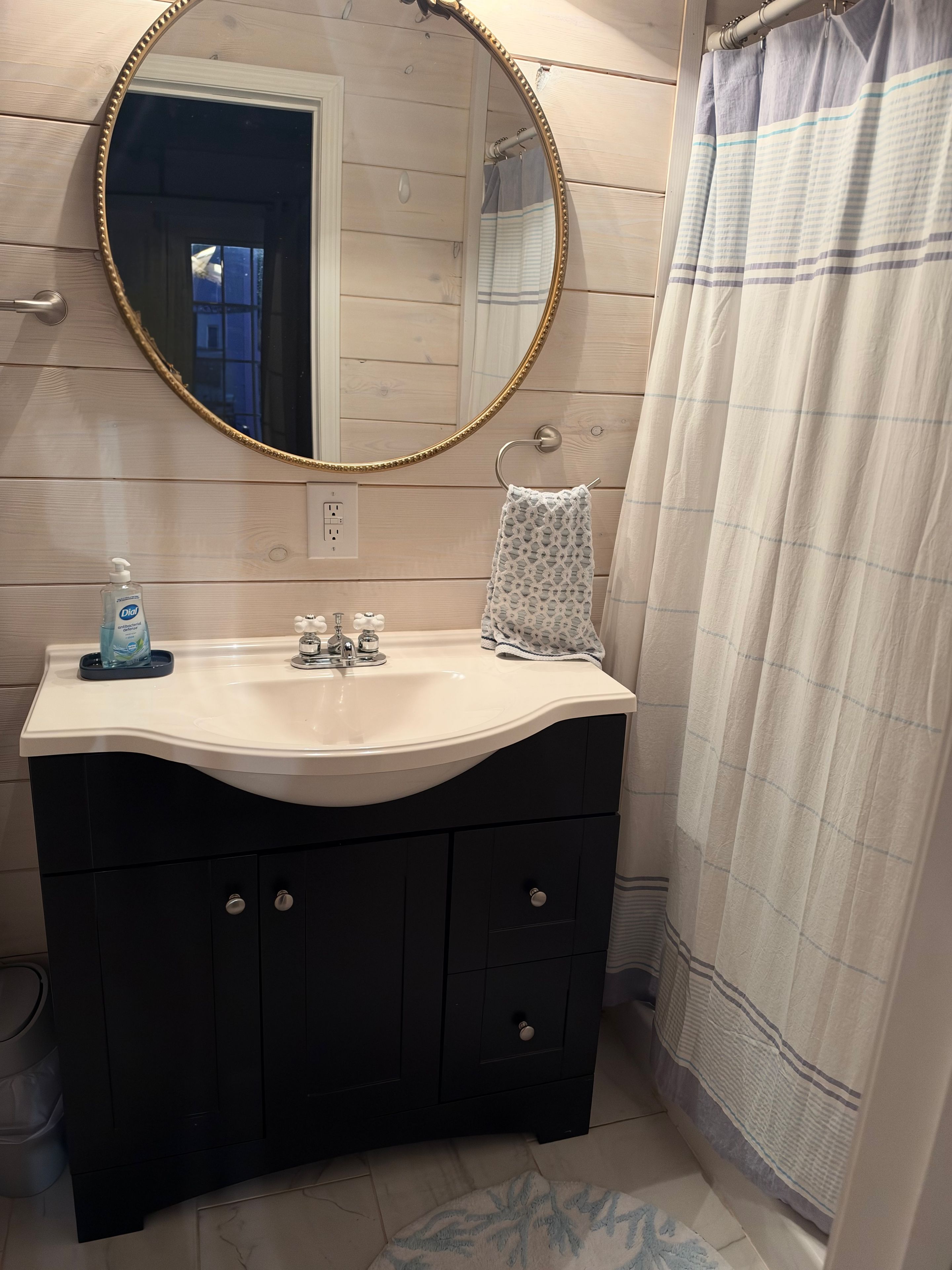 A bathroom with a vanity, a mirror, a sink, a towel, and a shower curtain.