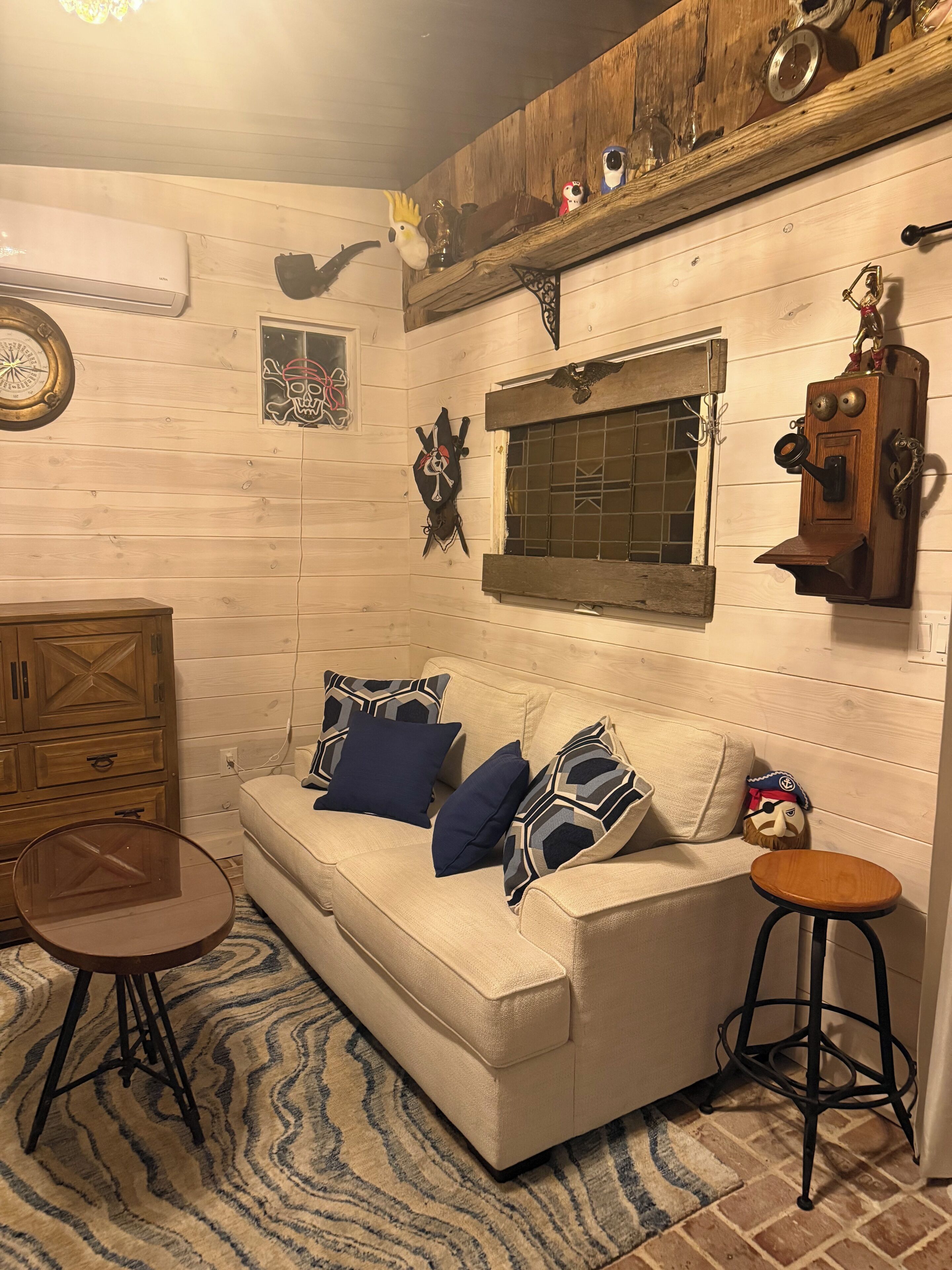 Une pièce chaleureuse avec un mur en bois, un canapé agrémenté de coussins à motifs, une petite table et un élément décoratif mural.