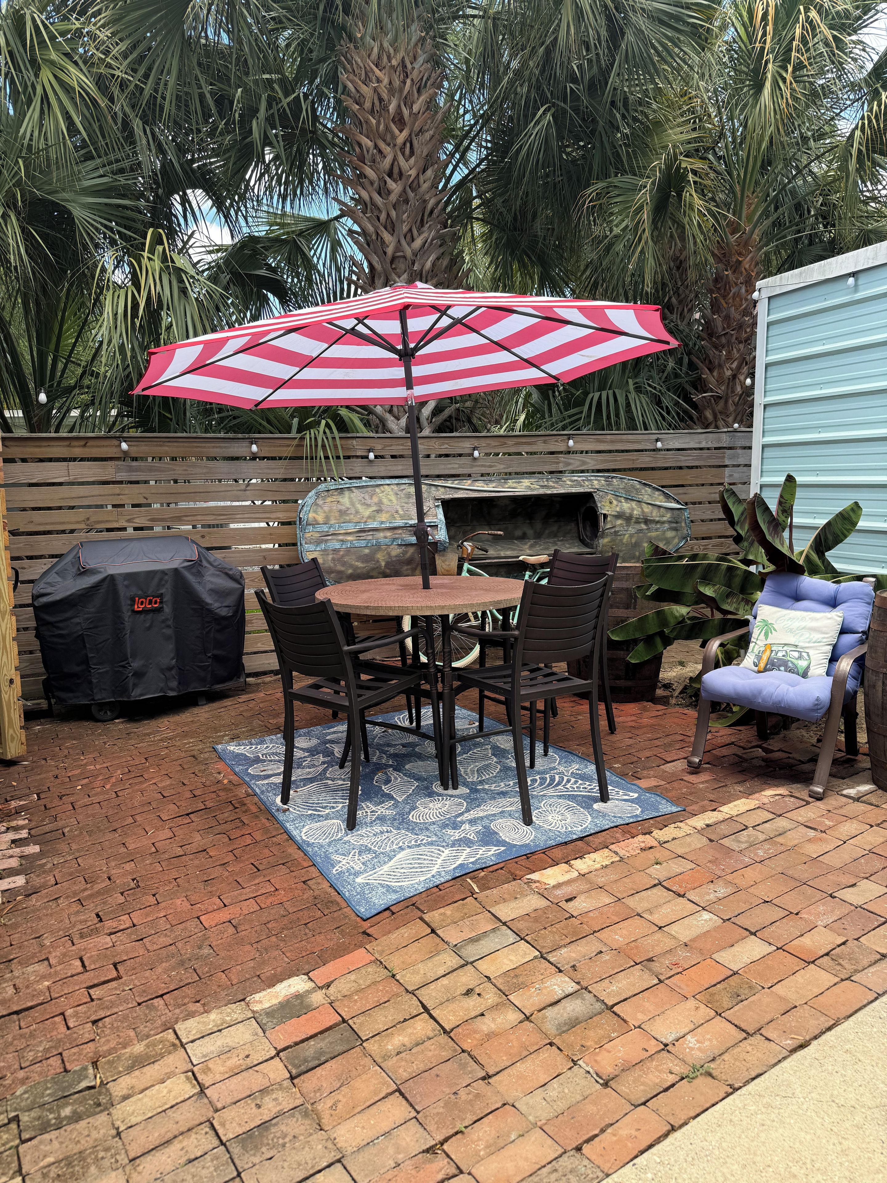An outdoor patio with a table and chairs, a grill, and a covered barbecue area.