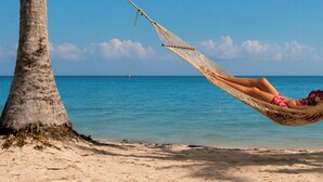 A hammock between two trees on a beach with the ocean in the background. - Matis Villa Private Pool (Vathi)