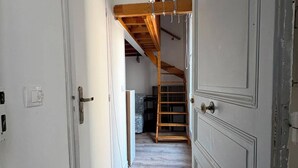 Ein schmaler Korridor mit Holzbalken, einer Erkerzone und einer Treppe.