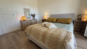 Ein Schlafzimmer mit einem Bett, Nachttischen, einem Spiegel und einer Topfpflanze.