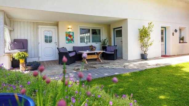 A covered patio area with outdoor furniture, a door, and a window. - Hinterseer Vacation Home (Ruhpolding)