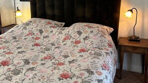 A bed with a floral bedspread, a dark headboard, and two bedside lamps.