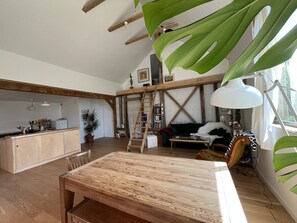Un amplio salón con una mesa de comedor de madera, un sofá y un ventanal que proporciona luz natural.