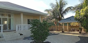A two-story building with a covered patio area, a small garden with gravel pathways, and a palm tree.