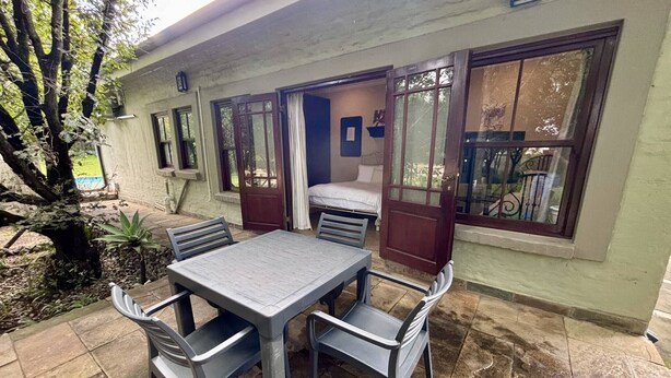 A patio with a table and chairs, a bed, and a window with curtains.