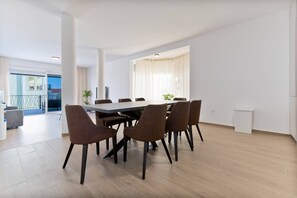Ein moderner Essbereich mit einem großen Tisch und sechs Stühlen, ein Balkon mit Geländer und Blick auf ein Gebäude.