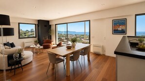 A modern living room with a dining area, large windows, and a view of the sea. - Contemporary villa with ocean views and a pool, sleeps 10, in Cavalaire-sur-Mer (Cavalaire-sur-Mer)