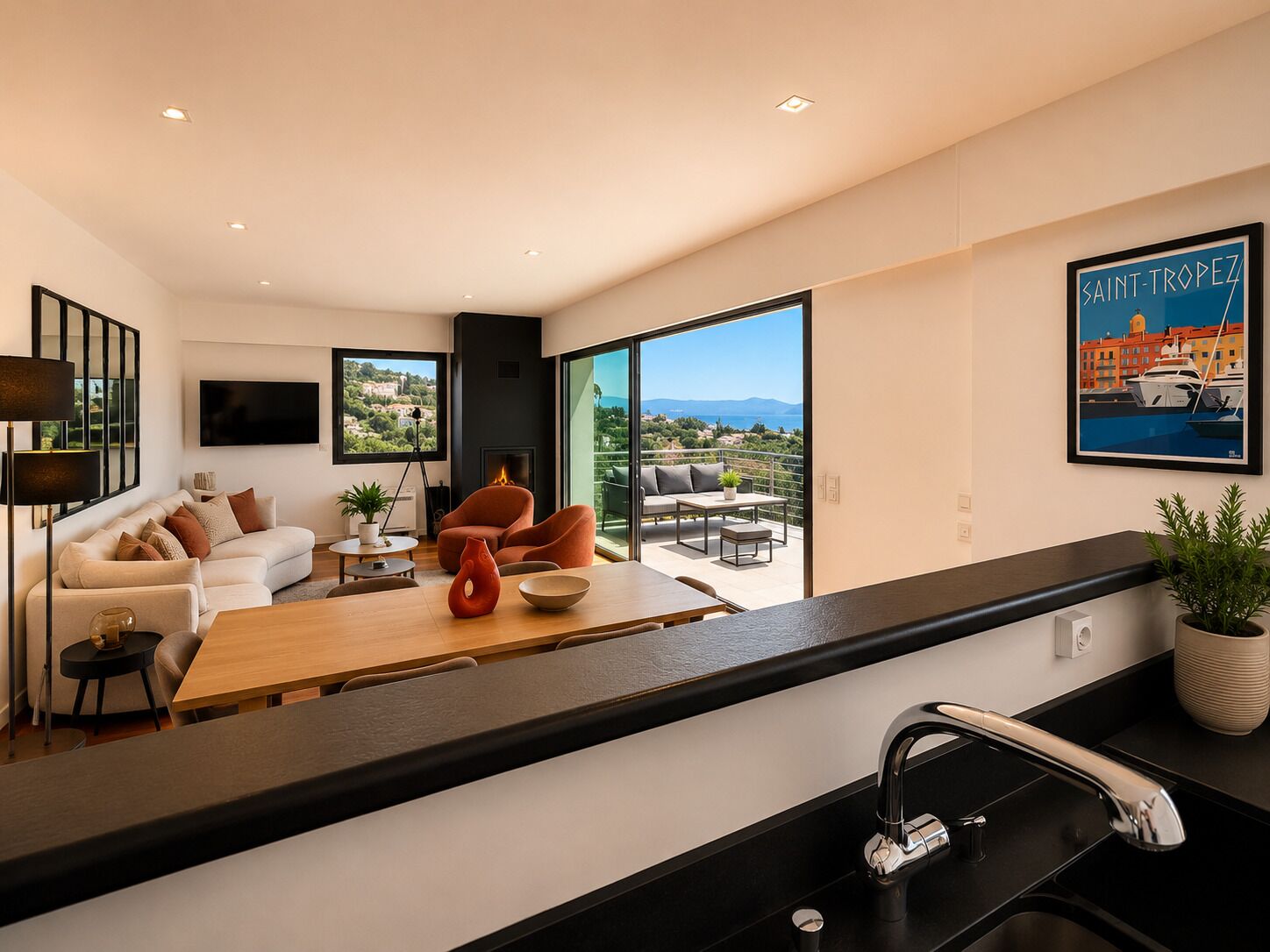 Una cocina moderna con una isla grande, un comedor con vistas y una sala de estar con sofá y televisor.
