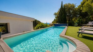A swimming pool with a wooden deck, a grassy area, and a modern building. - Contemporary villa with ocean views and a pool, sleeps 10, in Cavalaire-sur-Mer (Cavalaire-sur-Mer)