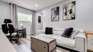 A modern living room with a white sofa, a small table, a desk, and a storage box. - Tranquil Retreat in Spring, The Woodland & Houston (Spring)