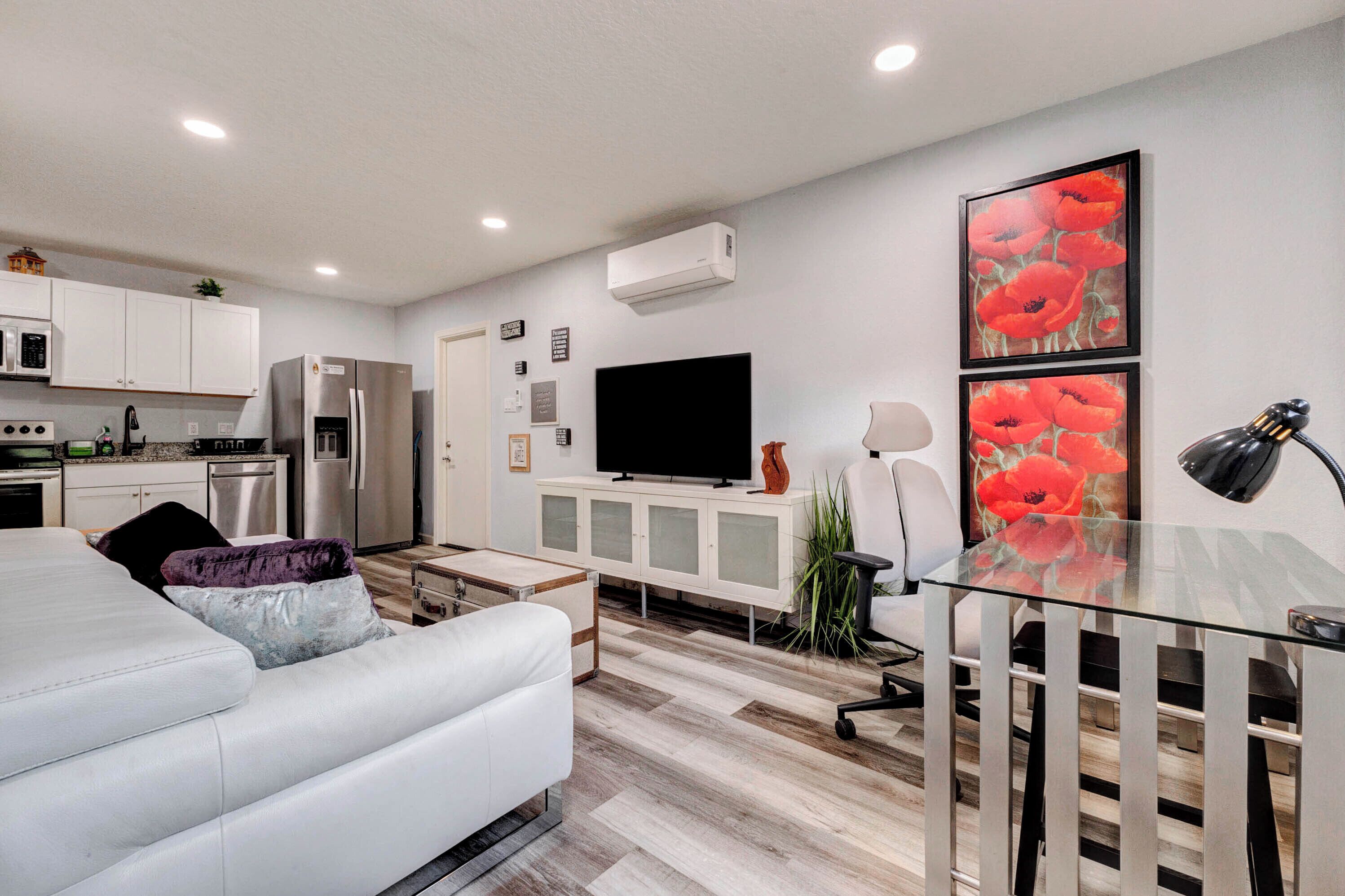 Una cocina moderna con gabinetes blancos, un refrigerador de acero inoxidable y un televisor de pantalla plana.