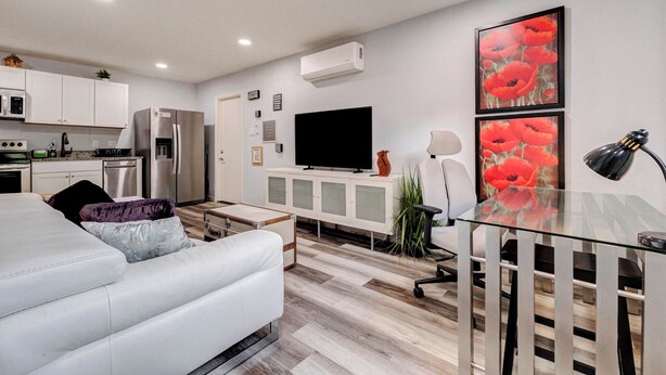A modern kitchen with white cabinets, a stainless steel refrigerator, and a flat-screen TV. - Tranquil Retreat in Spring, The Woodland & Houston (Spring)