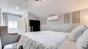 A bedroom with a bed, a chair, a television, and an air conditioning unit. - Tranquil Retreat in Spring, The Woodland & Houston (Spring)