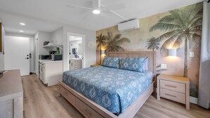 Ein Schlafzimmer mit einem Bett, Nachttischen, einem Deckenventilator, einer Klimaanlage und einer Wand mit einer Palmenmotiv-Wandmalerei.