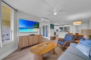 A modern living room with a wooden coffee table, a sofa, and a TV displaying a beach scene.