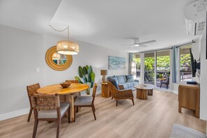 Ein modernes Wohnzimmer mit Essbereich, Deckenventilator und großen Fenstern.
