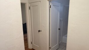Ein Flur mit Holzboden, weißen Wänden und zwei weißen Türen zu einem Badezimmer.