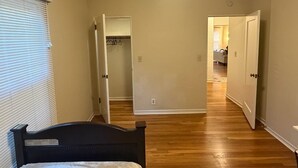 Ein Schlafzimmer mit Bett, Schrank und einem Gang zu einem weiteren Raum.