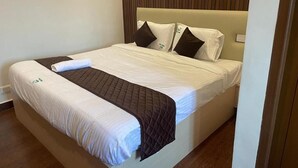 Una cama bien hecha con una colcha acolchada, dos almohadas y una toalla doblada.