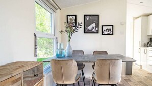 A dining area with a wooden table, beige chairs, a vase with flowers, and framed pictures on the wall. - Holiday Home in Linden With Terrace (Linden)