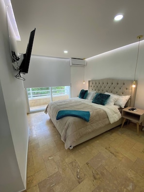Ein Schlafzimmer mit Bett, Nachttisch, Wand-Fernseher und Fenster.