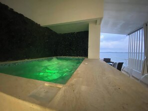 Ein Wellnessbereich mit Pool, einer Steinwand und Blick auf das Meer.