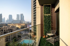 Ein Hochhaus mit Balkon, das einen Pool, einen Stuhl und eine vertikale Begrünung mit der Aufschrift 'Gogoto' zeigt.