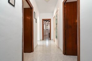 A hallway with wooden doors and a tiled floor, leading to a room with a glass door. - Casa Siboc – Mediterranean villa with a pool (Benissa)