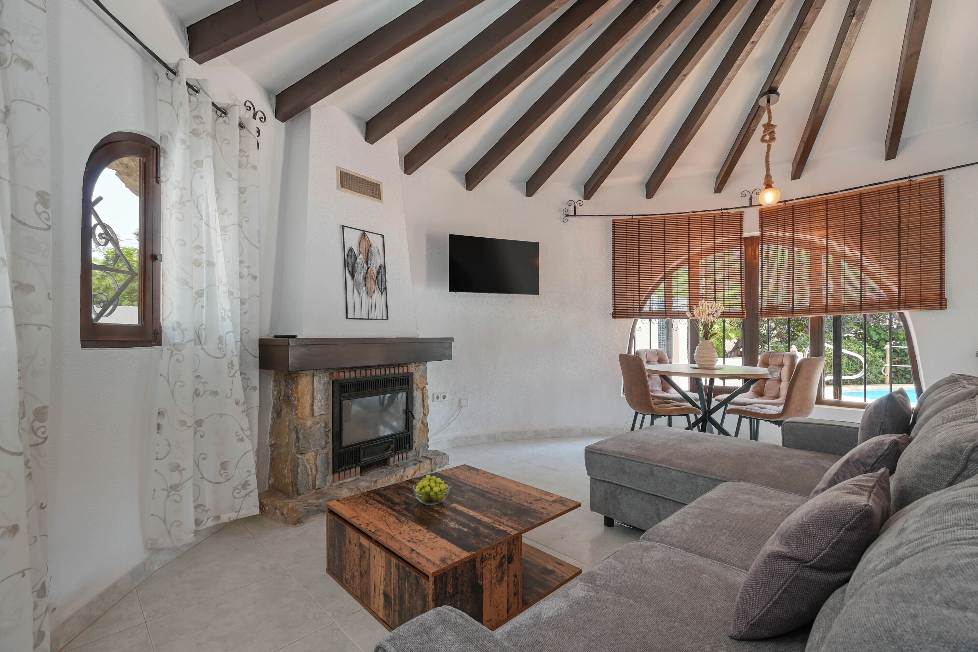 A living room with a fireplace, a sofa, a coffee table, and a dining area with chairs and a table.