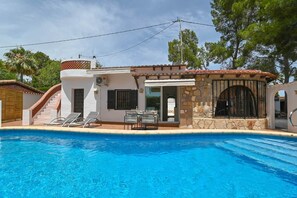 A residential property with a swimming pool, a patio with chairs, and a stone wall. - Casa Siboc – Mediterranean villa with a pool (Benissa)