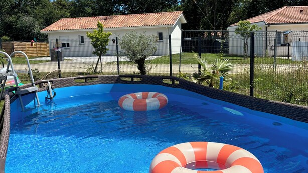En swimmingpool med parasol, redningskranse og stige.
