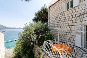 Ein Küstengebäude mit Balkon, Meerblick und einer Steinmauer.