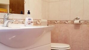 Baño con lavamanos, inodoro y una botella de jabón líquido.