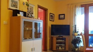 Una sala de estar con televisor, un mueble y una puerta.