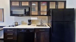 A modern kitchen with dark cabinetry, a microwave, a coffee maker, and a dishwasher.