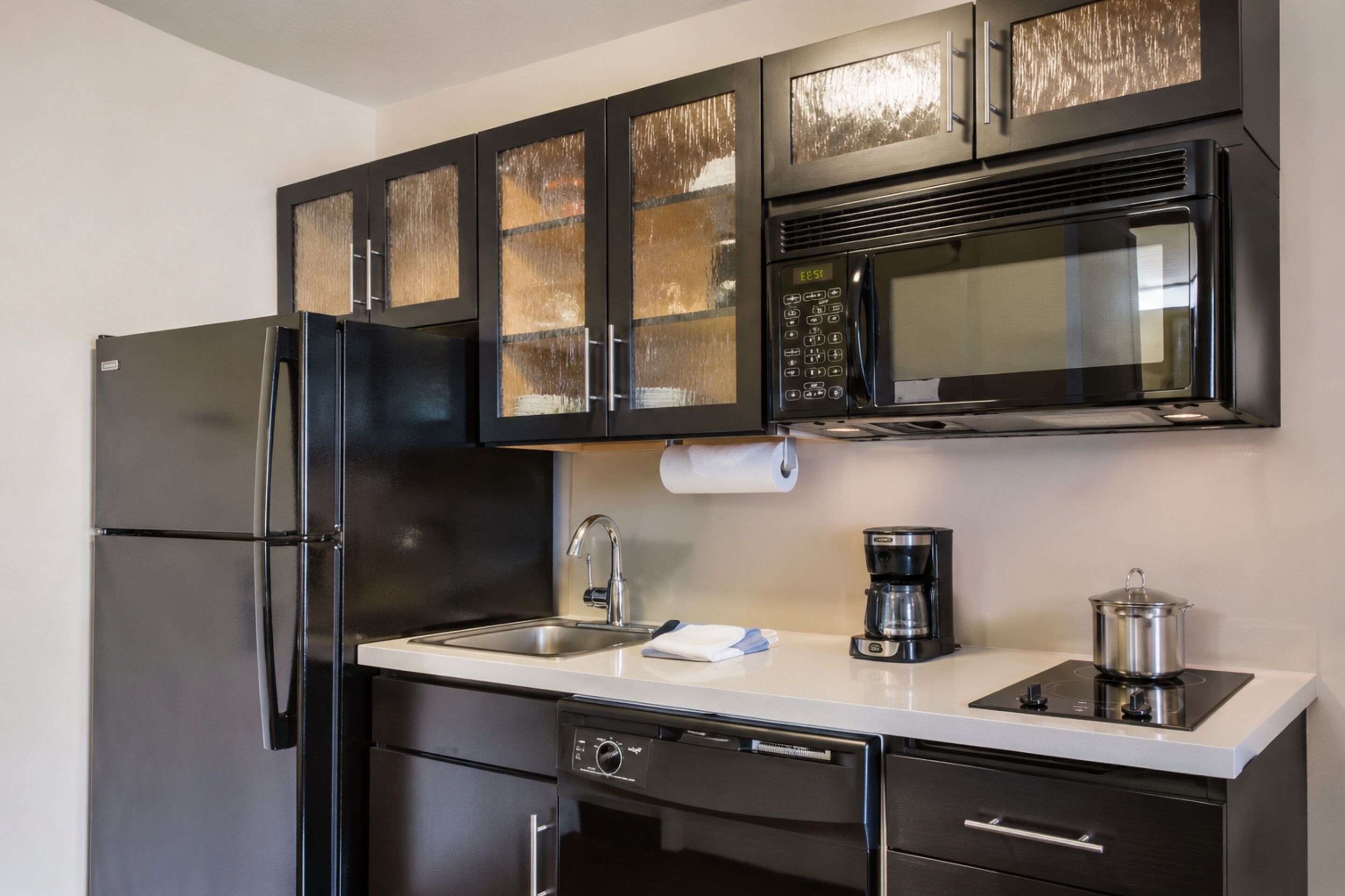 Een moderne keuken met een roestvrijstalen koelkast, een magnetron, een koffiezetapparaat en een vaatwasser.