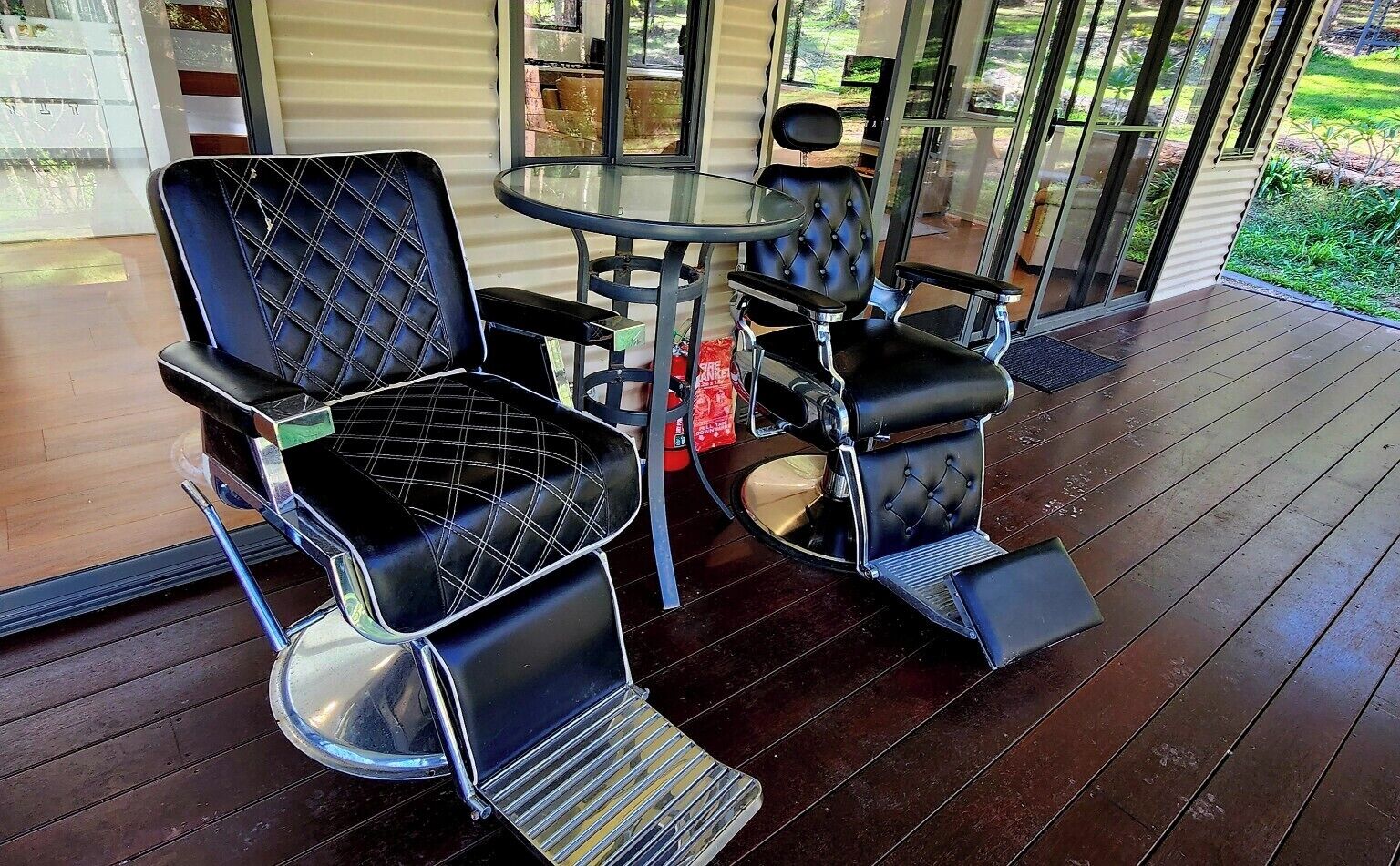 Un área de estar al aire libre cubierta con dos sillas negras y una mesa pequeña.