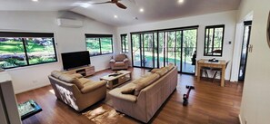 A spacious living room with a sofa set, a television, and a dining area with a table and chairs.