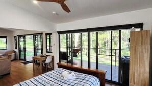 Quarto com uma janela grande, uma cama, uma escrivaninha e uma cadeira.