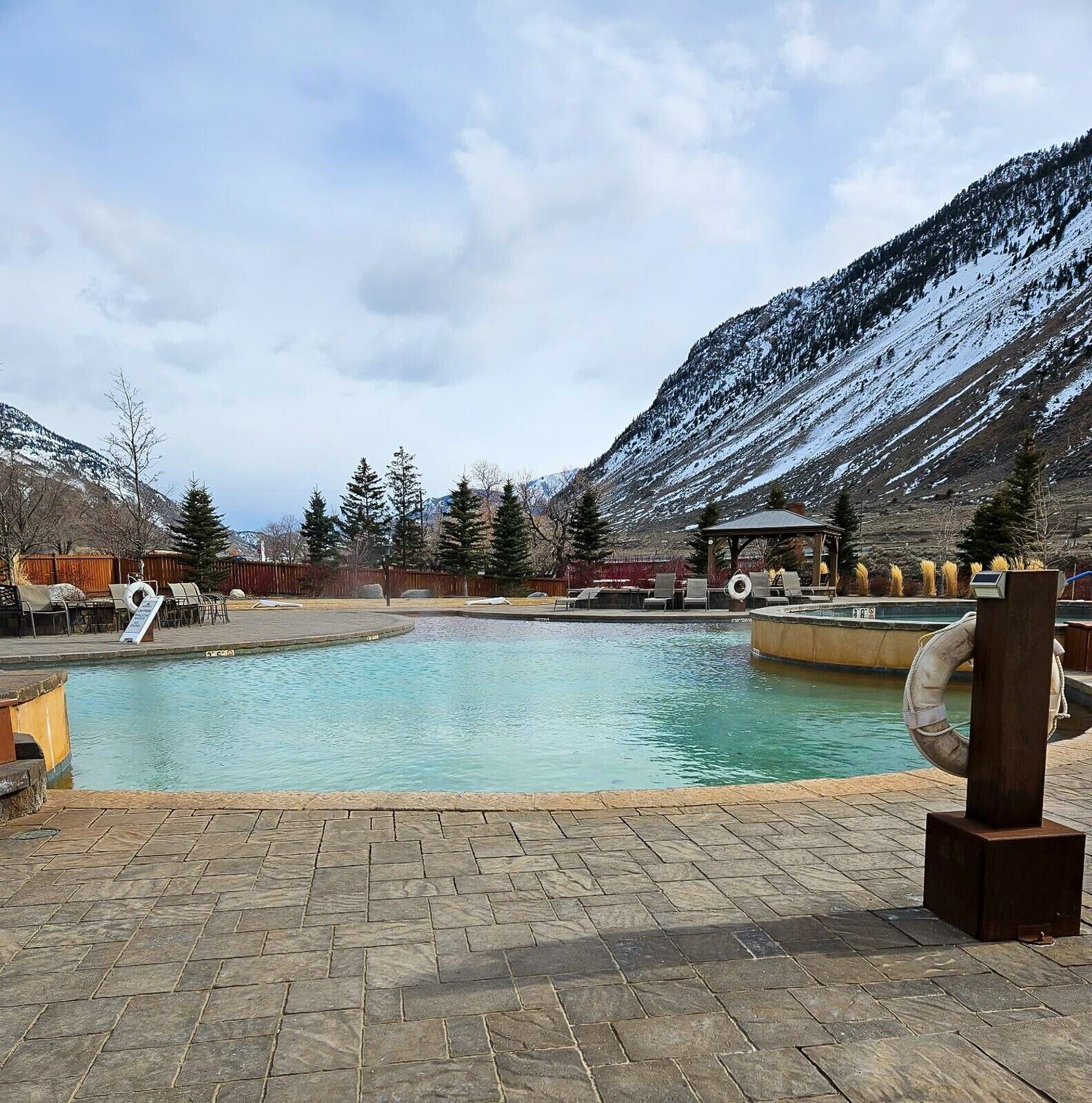Ein Poolbereich mit Holzterrasse, Liegestühlen und einem Rettungsring.