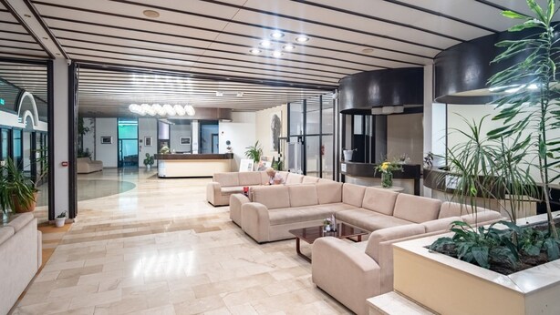 A modern lobby with a reception desk, beige sofas, a coffee table, and potted plants. - Hotel Issa - Double Room Sea View 3 (Vis)