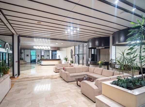 A modern lobby with a reception desk, sofas, and potted plants. - Hotel Issa - Double Room Sea View 3 (Vis)