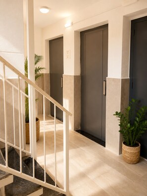 A modern hotel hallway with a staircase, doors, and potted plants. - Cala Pupi Terrace, quiet, cozy and bright accommodation (Segur de Calafell)